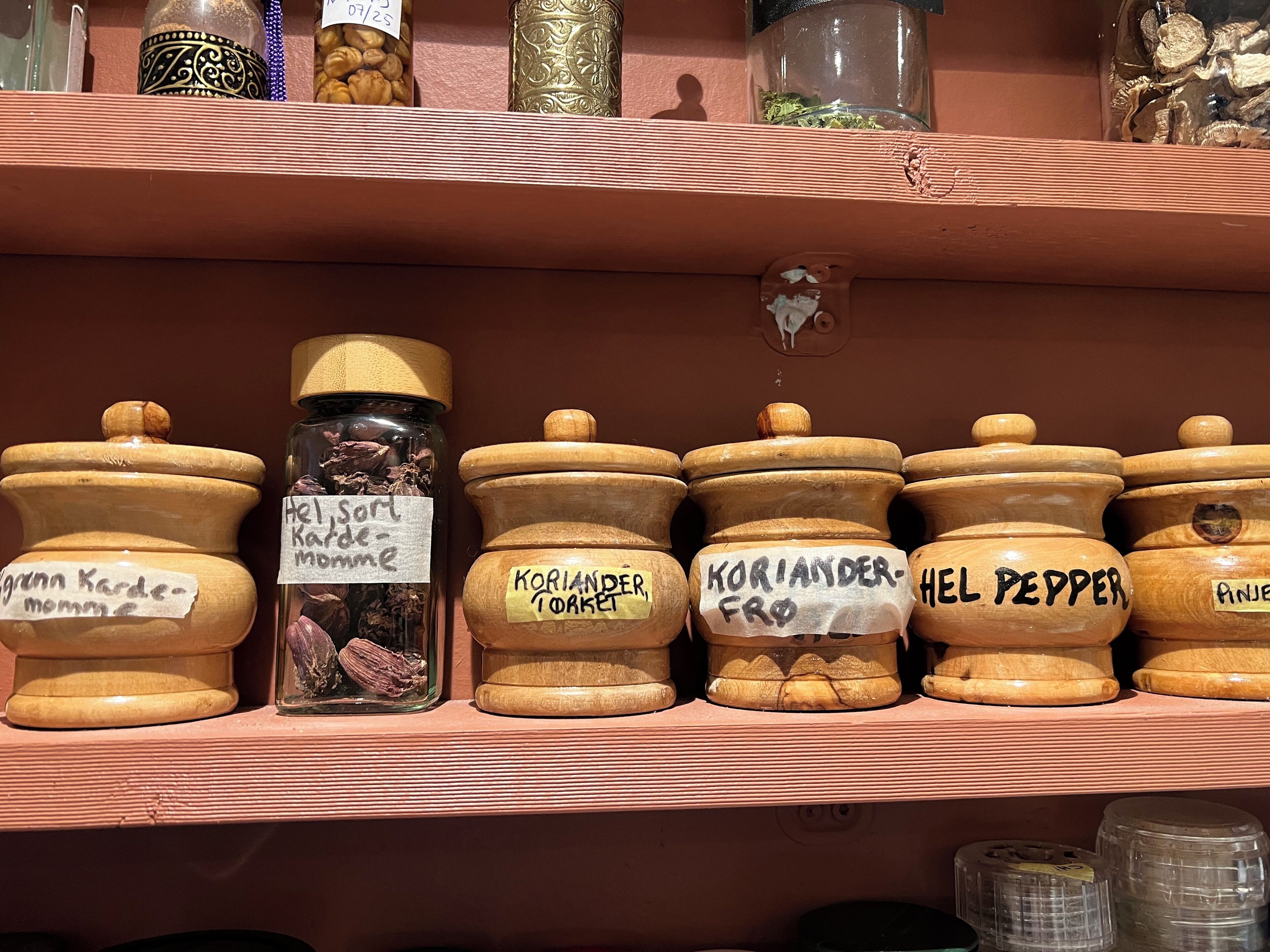 A shelf with various jars labeled with names of spices and herbs.