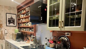 Una cocina con horno empotrado, un lavamanos y encimera de madera. Hay armarios, un microondas y una variedad de utensilios de cocina.