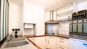 Une cuisine moderne dotée d’un évier à deux bacs, d’un four encastré et de meubles de rangement blancs.