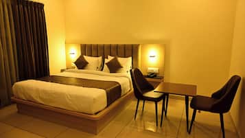 A hotel room with a bed, bedside tables, a desk, and chairs.