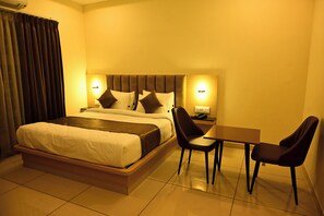 Una habitació d'hotel amb un llit, taules de nit, un escriptori i cadires.