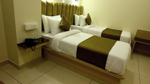 A hotel room with two single beds, a bedside table with a phone, and a wall socket.