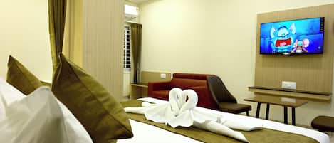 Une chambre d’hôtel avec un lit, une télévision, un bureau et un canapé rouge.