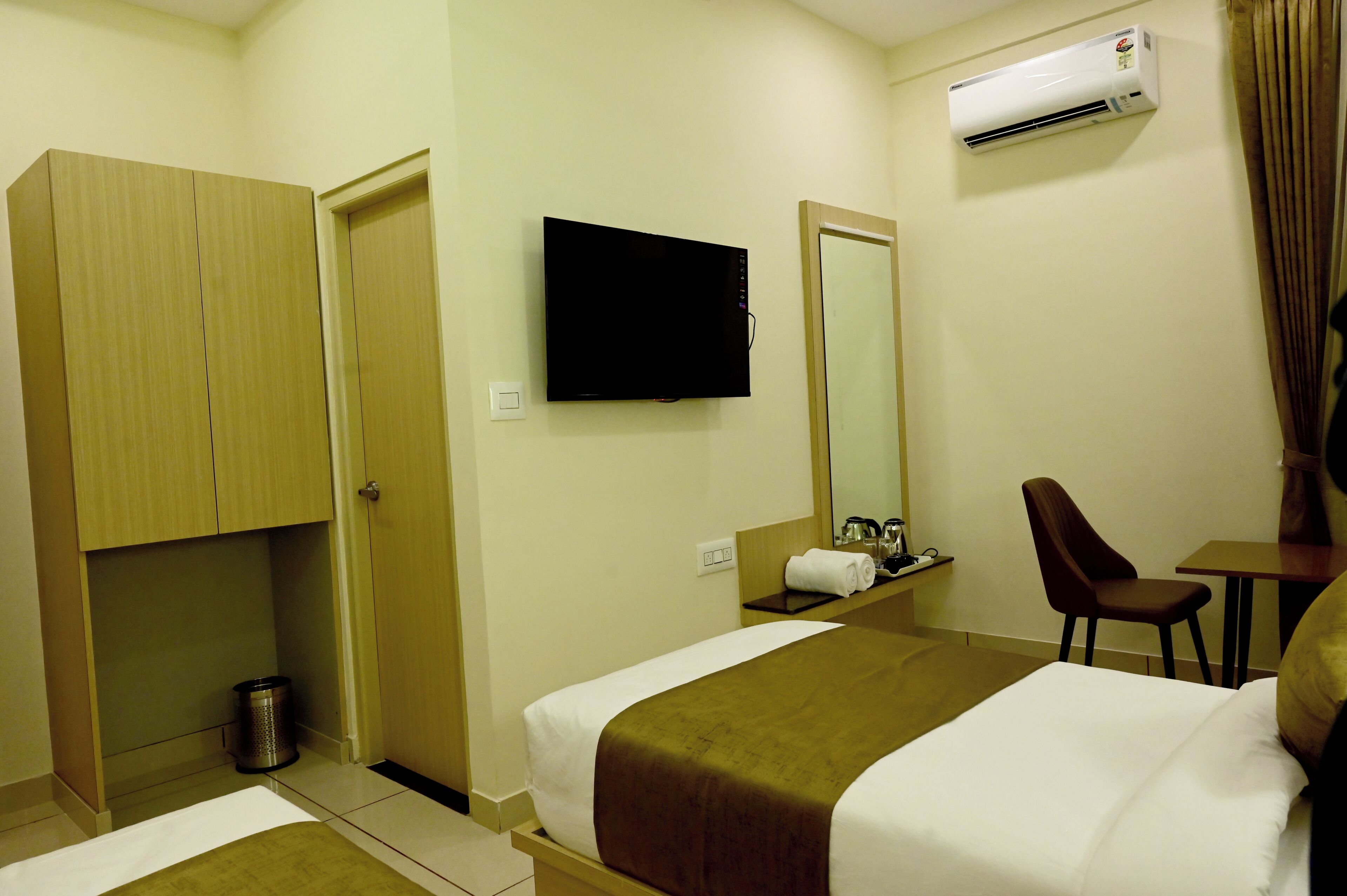 A hotel room with a bed, a television, a mirror, a desk, and a chair.