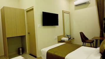 A hotel room with a bed, a television, a mirror, a desk, and a chair.