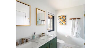 Un baño moderno con dos lavamanos, inodoro y ducha.