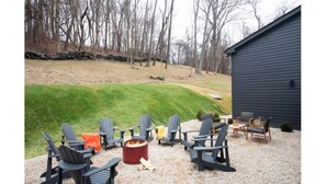 Un patio con sillas Adirondack, una fogata y una pequeña mesa.