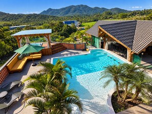 A pool area with a wooden deck, lounge chairs, and a covered seating area. - Sítio Recanto Pedacinho do Céu - Camboriú/SC (Camboriú)