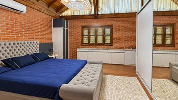 Un dormitorio con una cama grande, techo de madera, pared de ladrillo y una ventana con contraventanas.