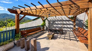 Un patio al aire libre con una pérgola de madera, un banco y una mecedora.