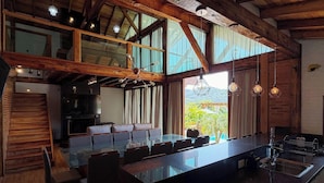 A spacious kitchen with a large island, wooden beams, and large windows offering a view of the outdoors. - Sítio Recanto Pedacinho do Céu - Camboriú/SC (Camboriú)