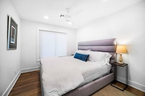 A bedroom with a bed, a nightstand, a ceiling fan, and a window. - Group Retreat | Hot Tub • Game Room • Walk to Main (Johnson City)