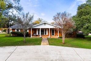 A single-story house with a front porch, a small front yard, and a clear sky. - Group Retreat | Hot Tub • Game Room • Walk to Main (Johnson City)