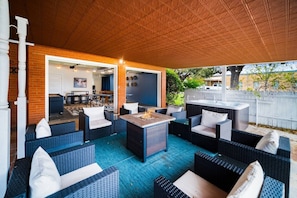 An outdoor patio with wicker furniture, a fire pit, and a view of the backyard. - Group Retreat | Hot Tub • Game Room • Walk to Main (Johnson City)