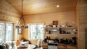 A wooden cabin interior with a dining area, kitchen, and a large window. - Private Sauna I 1.7 mi to Lutsen Mountain I Ski I Bike I Hike (Lutsen)