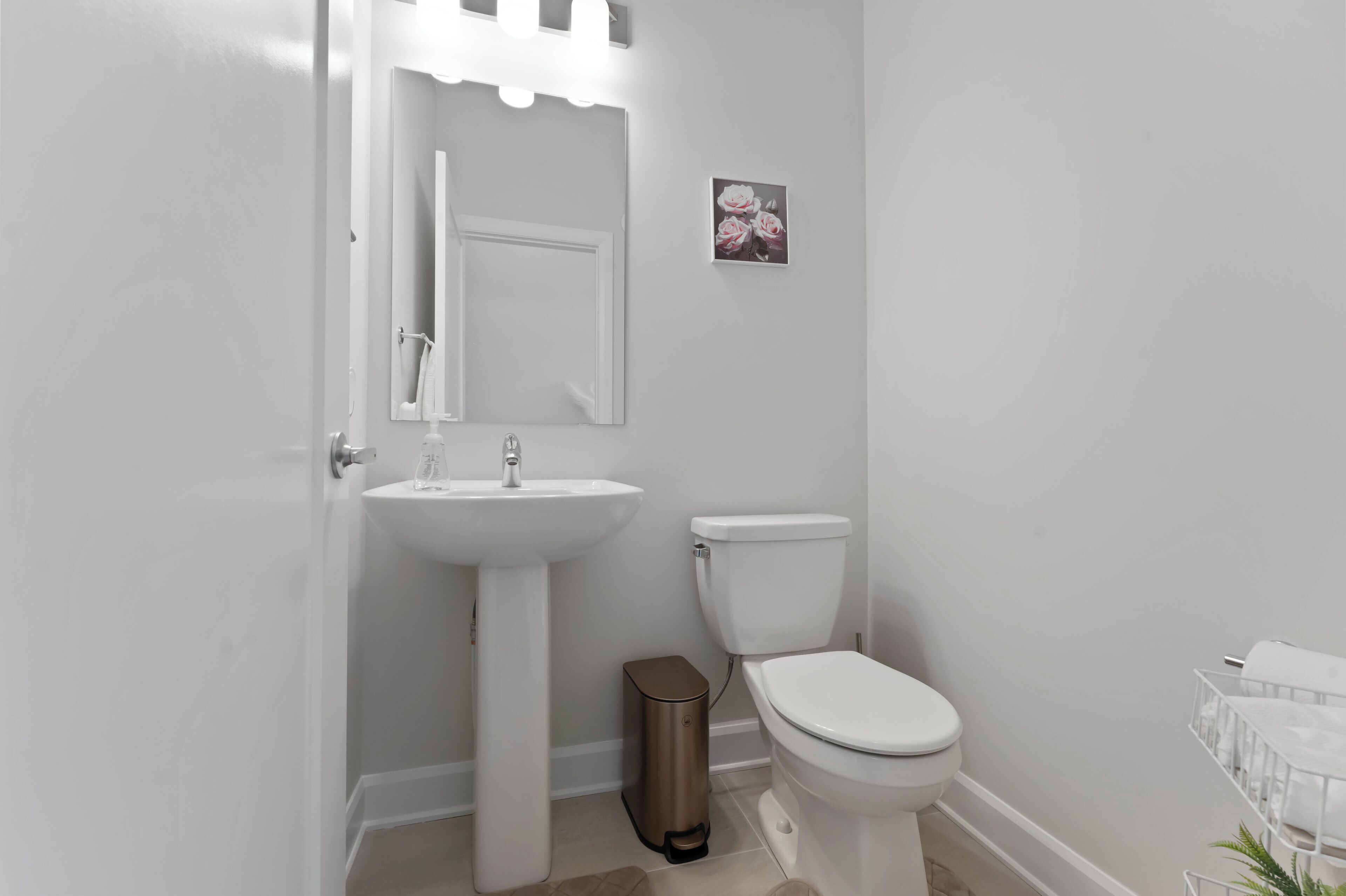 Een badkamer met een wit wastafelmeubel, toilet en een afvalbak.