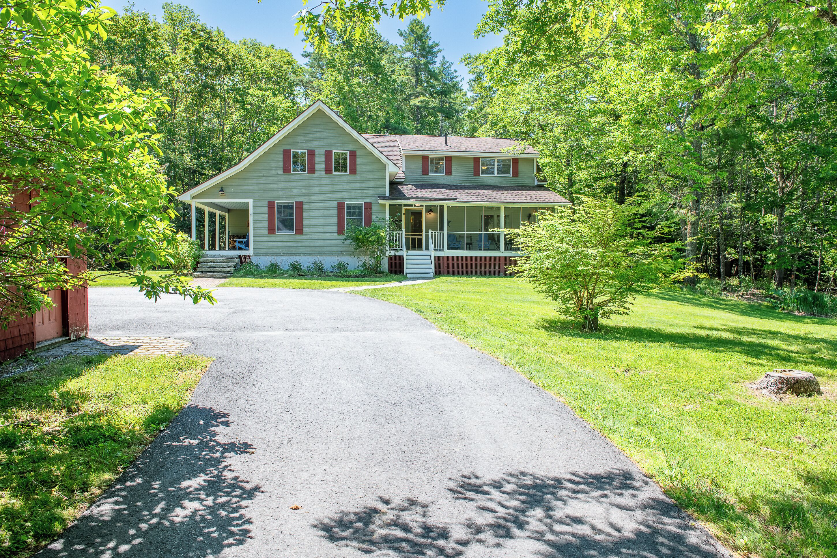 A two-story house with a covered porch and a driveway leading to the front door.