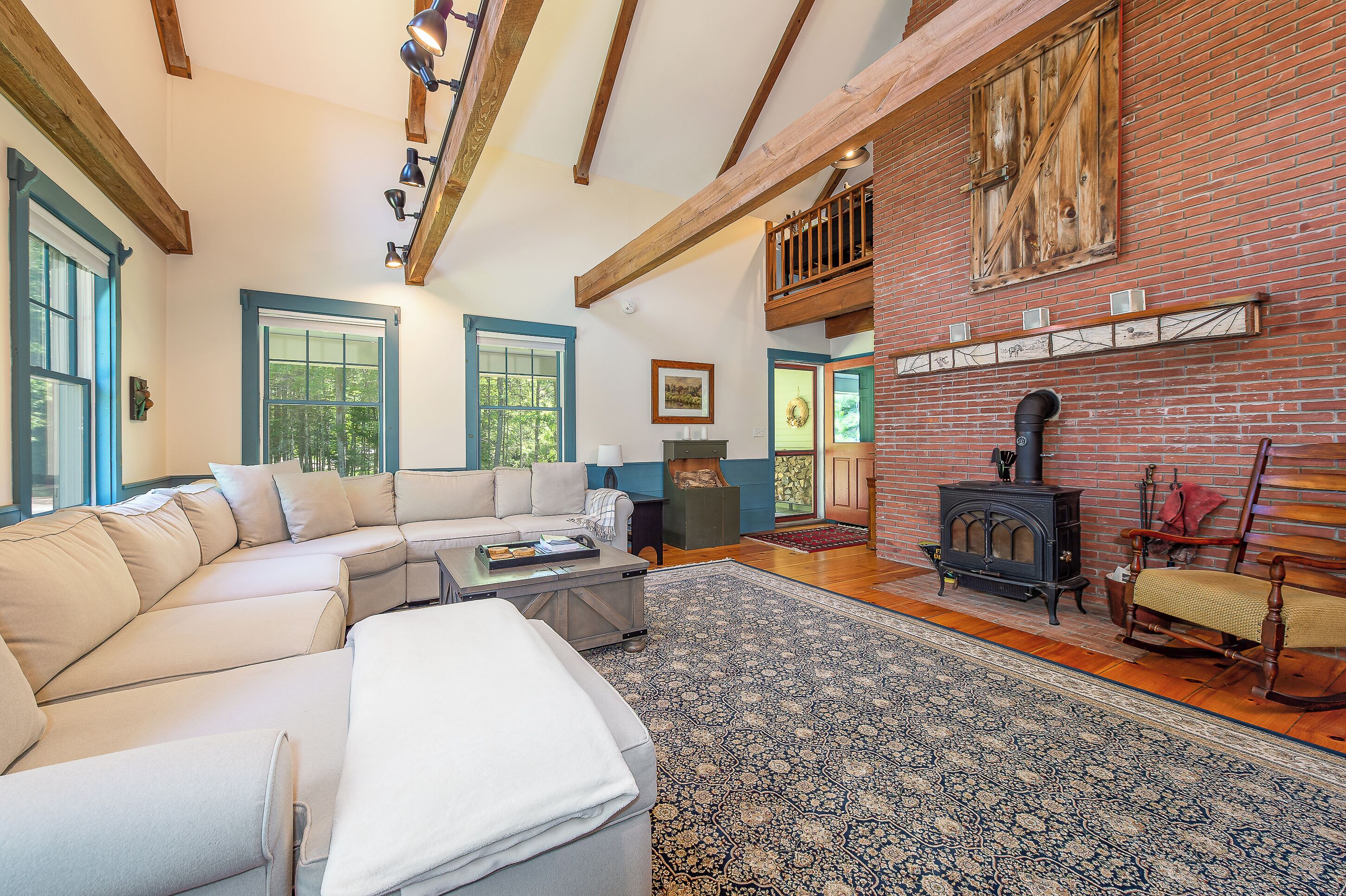 A spacious living room with a sectional sofa, a fireplace, and a large window.
