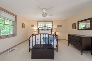 A bedroom with a bed, a dresser, a ceiling fan, and a window. - Heron's Perch Beautiful Pondside Home with Screened Porch (Brunswick)