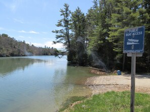 A serene lake with a public boat access sign, surrounded by dense trees and a clear sky. - Heron's Perch Beautiful Pondside Home with Screened Porch (Brunswick)