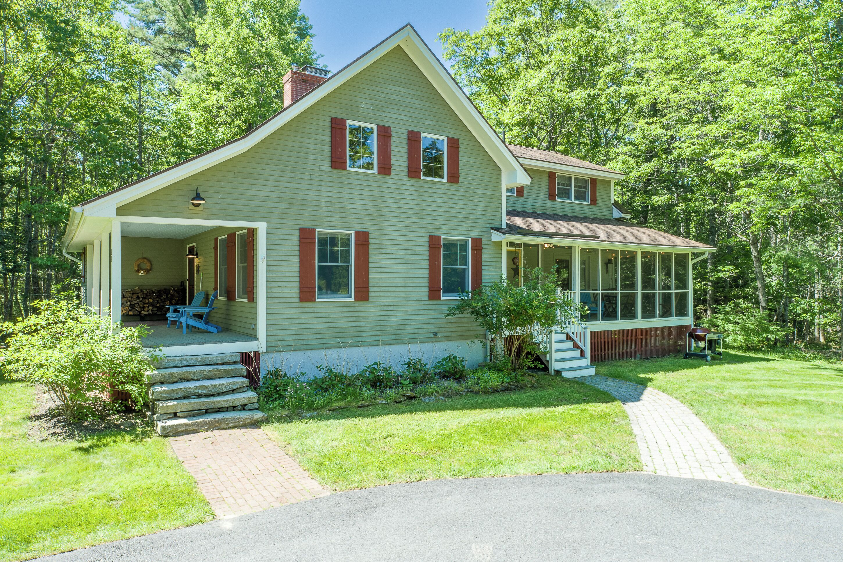 A two-story house with a porch, a covered front porch area, and a stone staircase leading to the entrance.