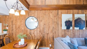 Une pièce aux murs lambrés, comprenant une table à manger, des chaises, un canapé et des œuvres d’art accrochées au mur.