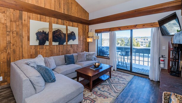 Un salon avec un mur en bois, un canapé, une table basse et une grande fenêtre donnant sur un beau paysage.