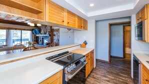 Une cuisine moderne avec des meubles en bois, une grande cuisinière et un coin repas avec des chaises.
