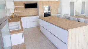 Een moderne keuken met witte kasten, een houten aanrechtblad, een ingebouwde magnetron en een flatscreen televisie.