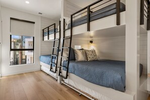 Quarto com beliche, janela e mesa de cabeceira.