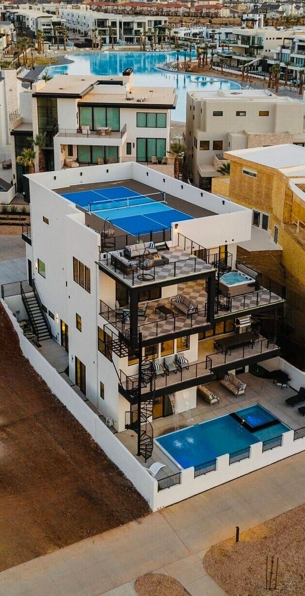 Um edifício com vários andares, piscina no terraço, área de estar ao ar livre e varanda no segundo andar.
