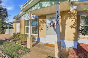 A residential house with a brick facade, a white door, and a wreath on the door.