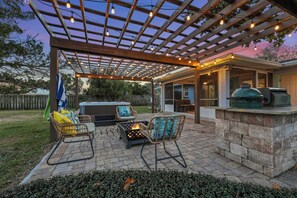 Una terrazza esterna con una pergola, zona salotto e stazione barbecue.