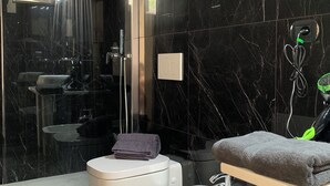 A modern bathroom with a black marble floor, a glass-enclosed shower with purple lighting, a white toilet, a bidet, and a vanity with a towel. - NATIONAL GALLERY TAORMINA ROOMS WITH PRIVATE BATHROOM SHARED KITCHEN AND BALCONY (Taormina)