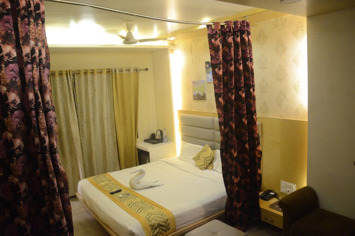 A hotel room with a bed, a nightstand, a chair, and curtains.