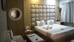 A hotel room with a large bed, a round mirror, a wooden wardrobe, and a small table with a remote control. - HOTEL  RAJ PALACE SHIVPURI (Shivpuri)