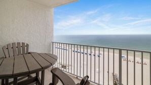 Ein Balkon mit Blick auf den Strand, einem Tisch und Stühlen.