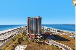 A high-rise hotel with multiple balconies overlooking a beach and ocean. - 🌴🌊15th Floor Gulf and Sound Views | Newly Renovated | Portofino 1-1502 (Pensacola Beach)