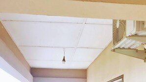 A balcony with potted plants, a door, and a view of buildings. - Cozy Studio Apartment in Vibrant Spintex, Accra (Accra)