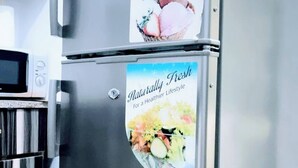 A stainless steel refrigerator with two stickers: one advertising energy efficiency and the other promoting a healthy lifestyle. - Cozy Studio Apartment in Vibrant Spintex, Accra (Accra)