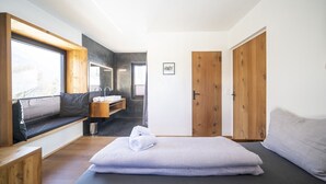Ein modernes, kompaktes Schlafzimmer mit eingebauter Sitzbank, Nachttisch und großem Fenster.