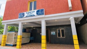 A two-story hotel with a red and beige facade, a covered entrance, and yellow pillars. - Blessing Select DLF (Chennai)