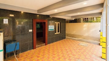 Un hall d’hôtel avec un sol carrelé, un comptoir de réception, une porte donnant accès aux chambres et une enseigne indiquant le nom de l’hôtel.