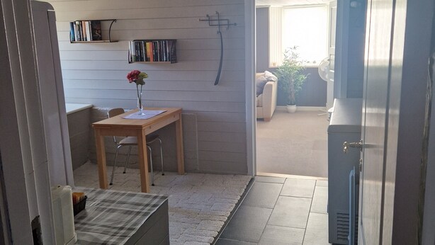 A compact kitchen with a refrigerator, a dining table with chairs, and a small rug. - Quaint 1-bedroom basement apartment in charming Vestland (Vestland)