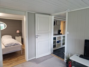 Un dormitorio con cama, mesita de noche, lámpara y armario con estantes.