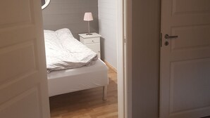 A bedroom with a bed, a bedside table with a lamp, and a door. - Quaint 1-bedroom basement apartment in charming Vestland (Vestland)