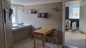 A compact kitchen with a wooden table and chairs, a built-in shelf with books, and a window. - Quaint 1-bedroom basement apartment in charming Vestland (Vestland)