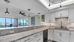 Una cocina moderna con armarios blancos, encimera de granito y lavavajillas integrado.