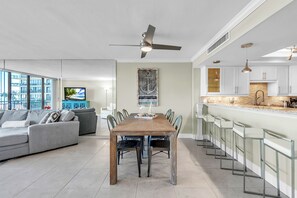 Un saló modern amb zona de menjador, cuina i una finestra gran que dona a una vista urbana.
