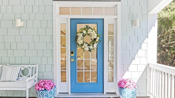 A blue door with a wreath, white bench, and two potted plants on a porch. - "One Particular Harbor" BHI and Shoals Club, 5 BR 3.5 BA, New Rental 2026 (Bald Head Island)